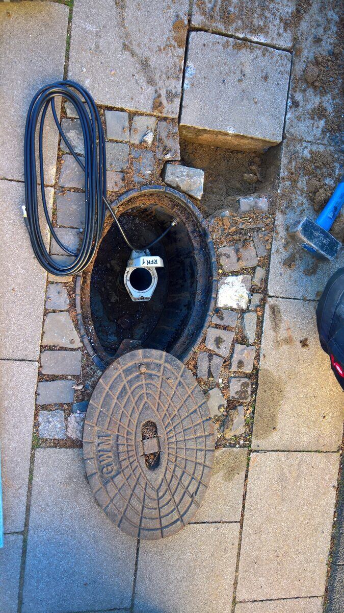 Unterflur-Pegelschacht: geöffneter Deckel, Sondenkabel und Schacht­abdeckung zur Wartung herausgenommen.