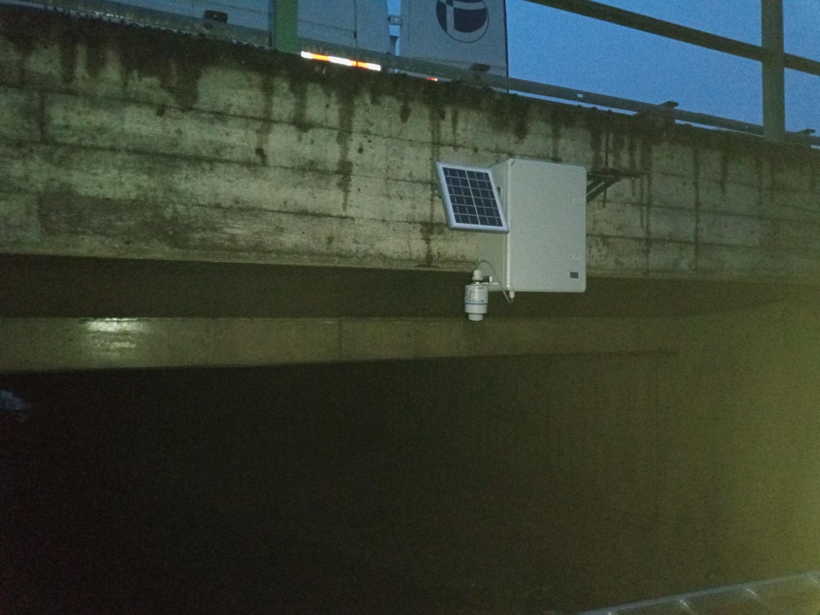 Solar-datalogger bij een snelwegbrug in de schemering, sensor in de onderdoorgang