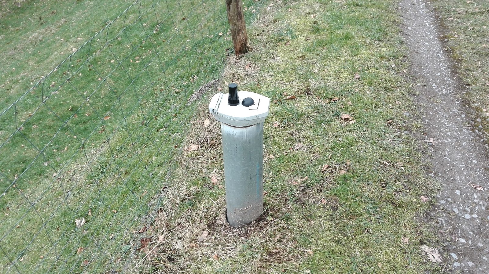 Klassieke grondwater-peilbuis op het veld met beschermkap en peilbuis